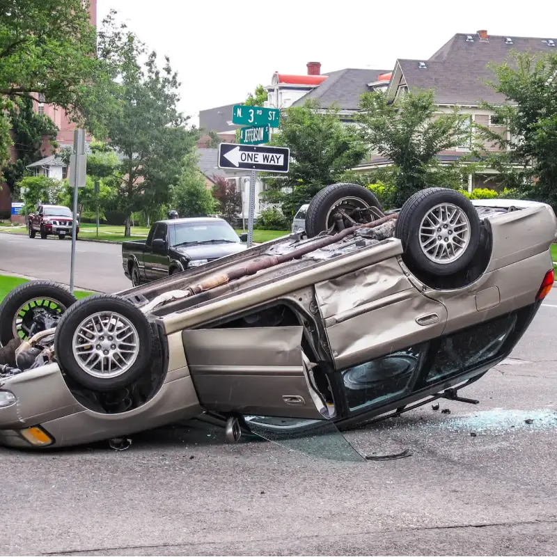 Rollover car accident involving a silver vehicle overturned on a street, illustrating the dangers associated with such incidents, relevant to personal injury law and legal representation for victims.