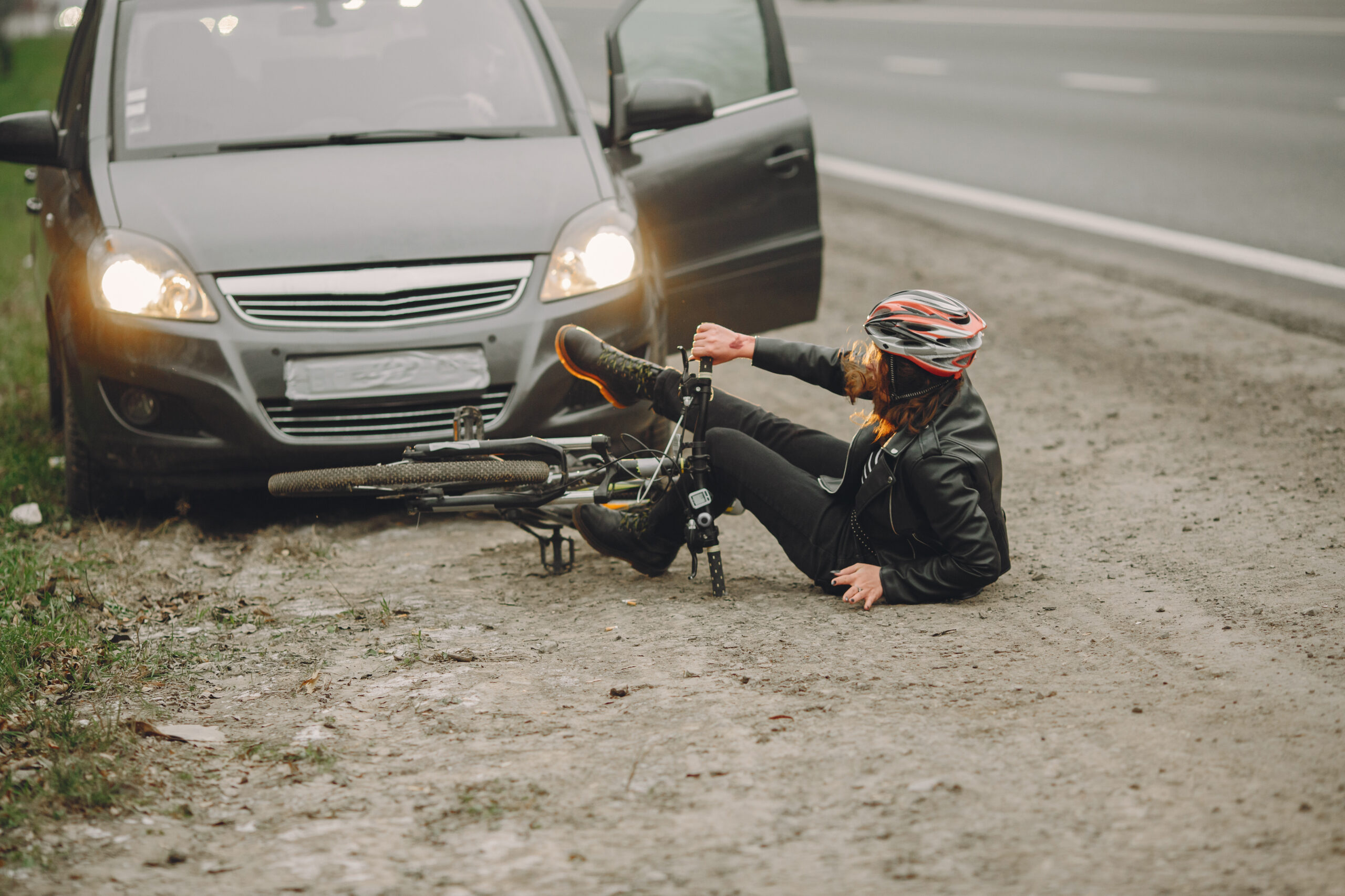 Bicycle accident scene with a woman on the ground near a car, emphasizing personal injury and the need for legal assistance in Brazoria County.