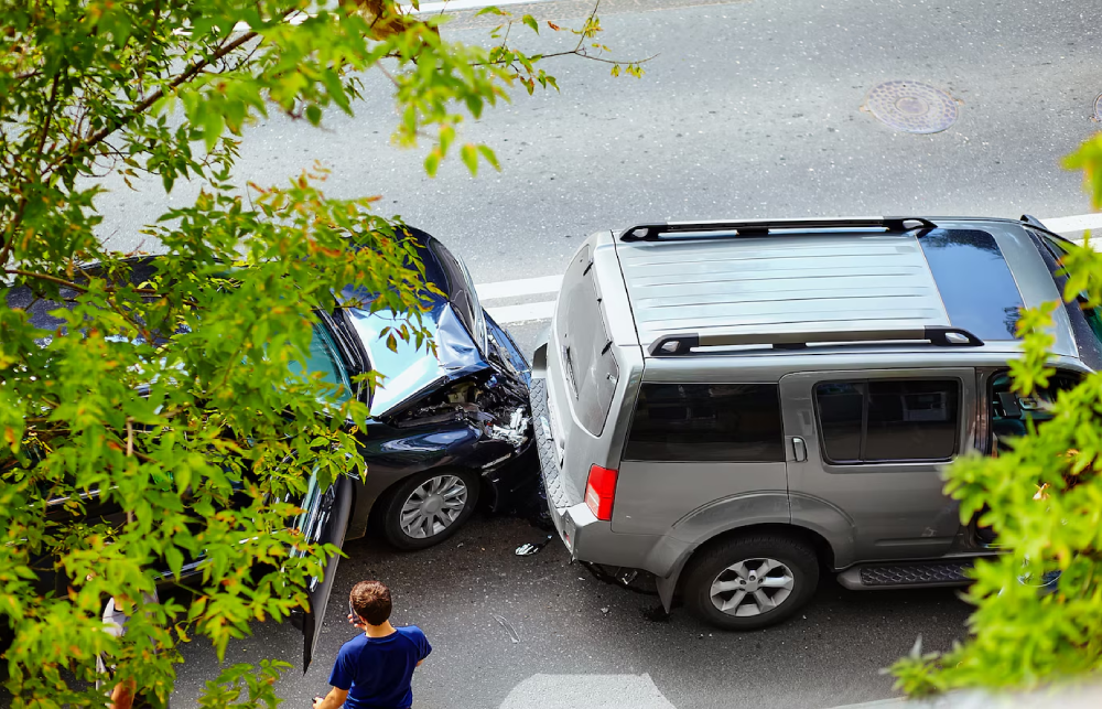 Car accident scene with a damaged black sedan and a gray SUV on a street, highlighting the risks of uninsured motorists in Texas.