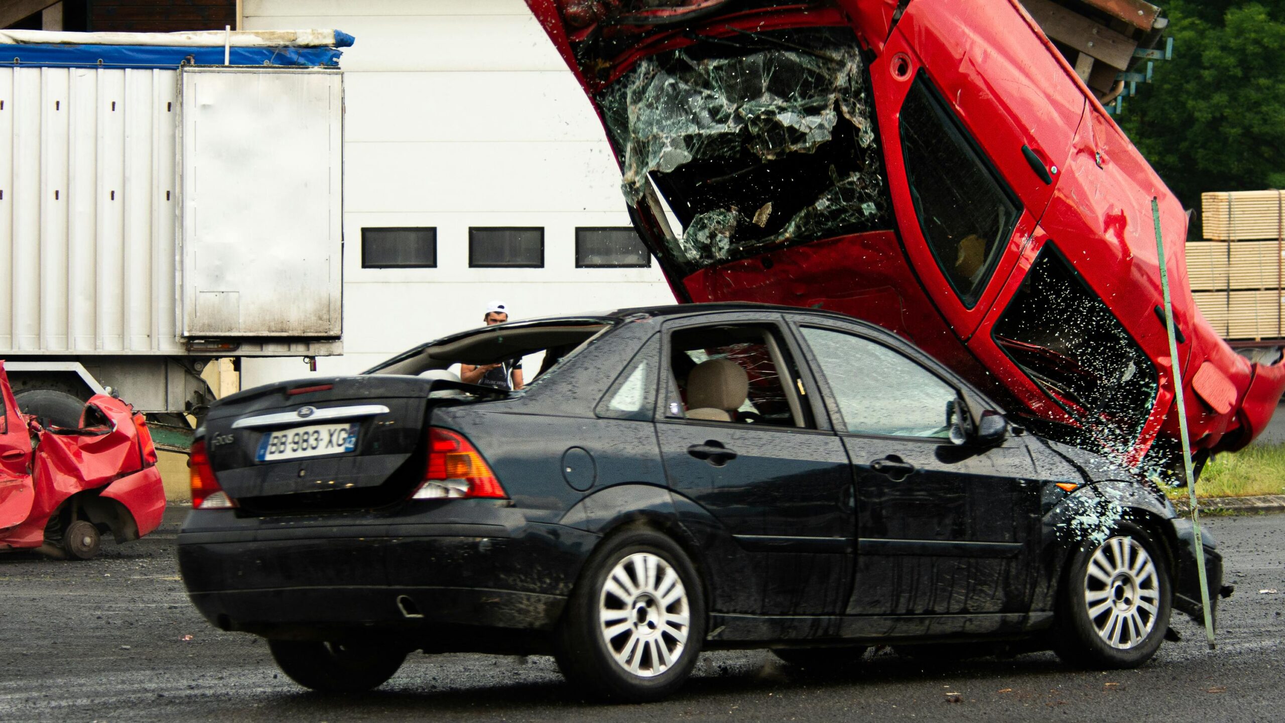 Car accident scene with a black sedan and a flipped red car, illustrating the dangers of vehicle collisions and personal injury risks.