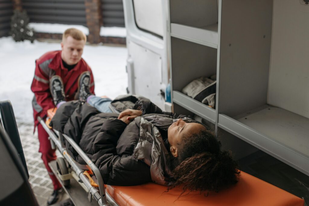 Emergency medical technician assisting injured woman on stretcher in ambulance, highlighting personal injury response and care.