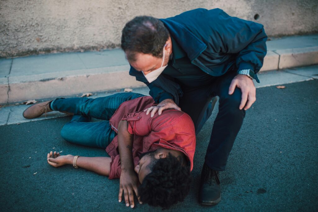 Person assisting an injured individual on the ground, highlighting the urgency of personal injury situations, relevant to legal advocacy in Culebra Park.