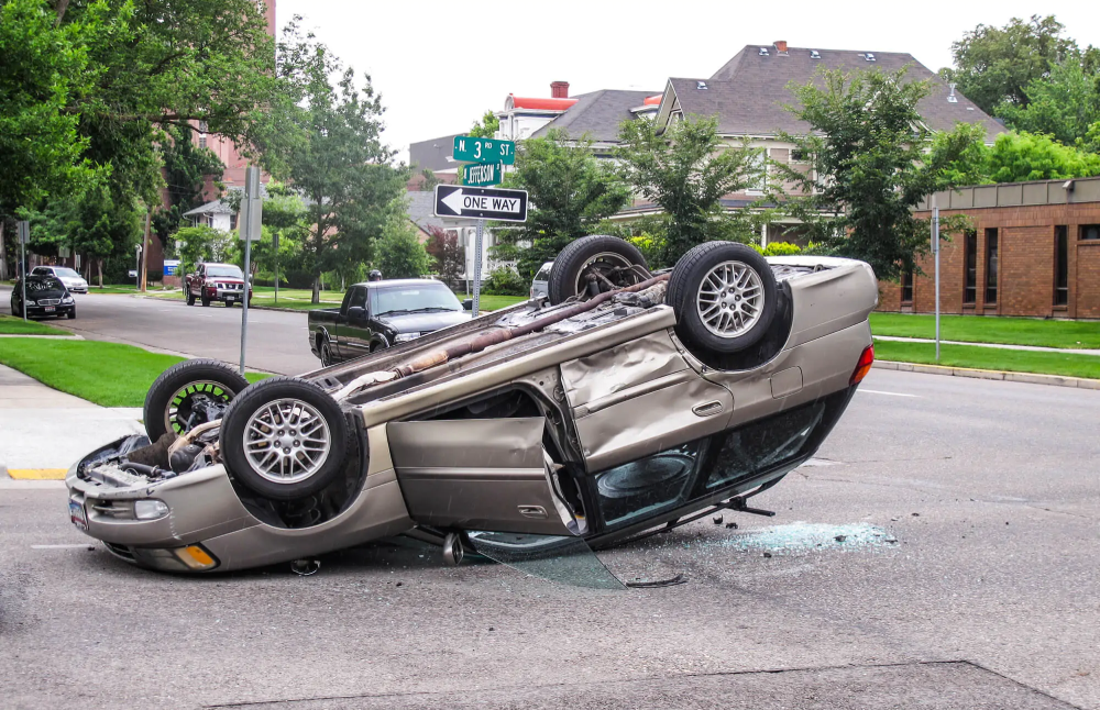 Rollover accident scene showing an overturned vehicle on a city street, illustrating the dangers of vehicle design defects and poor road conditions.