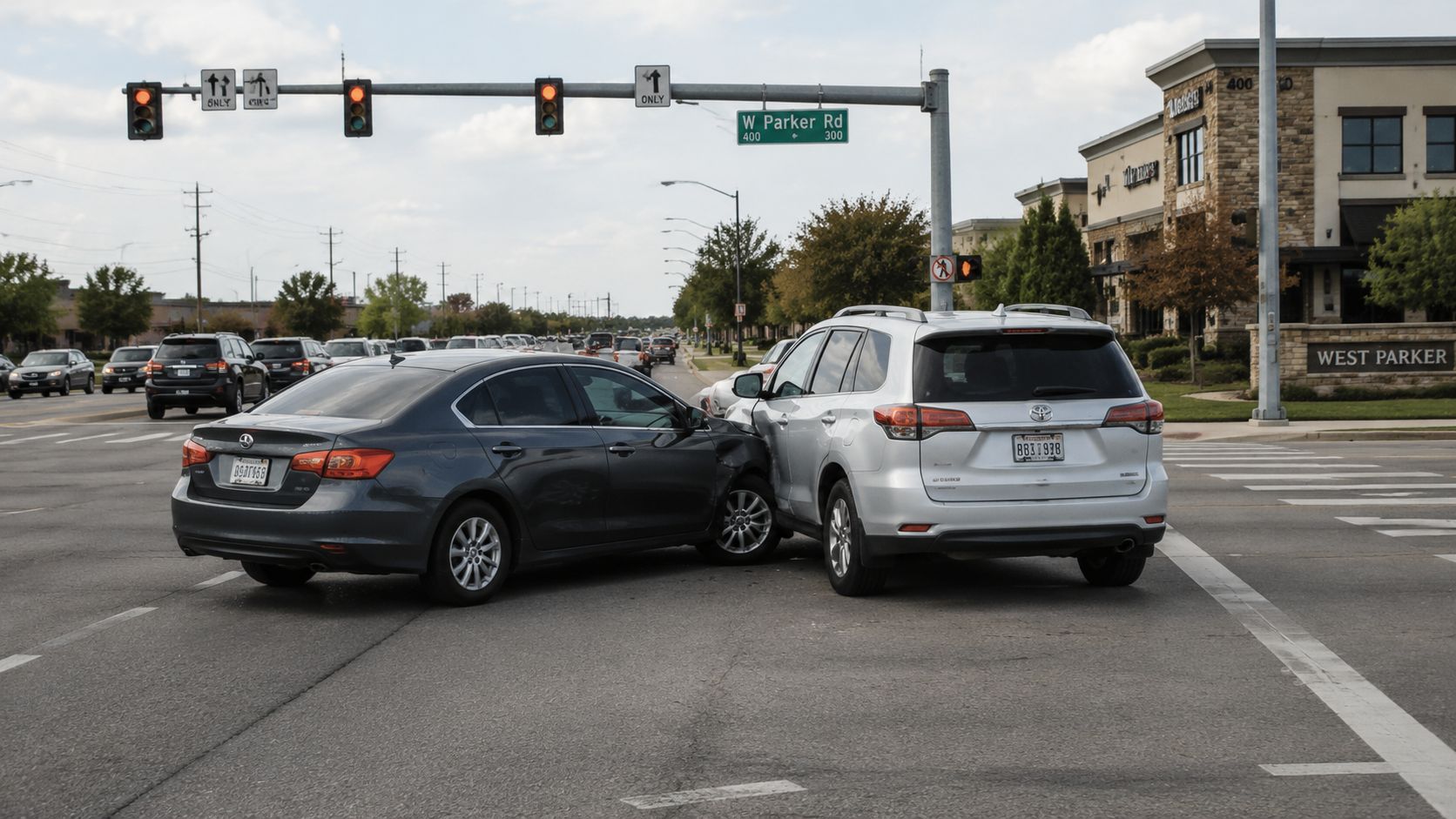 A silver SUV and a dark gray sedan involved in a car accident at a road intersection.